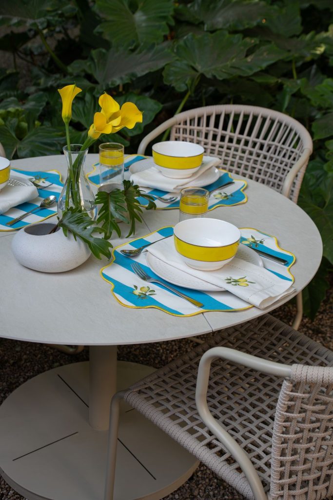 Foto ambientada de uma mesa com jogo americano e guardanapos com bordado de limão siciliano.