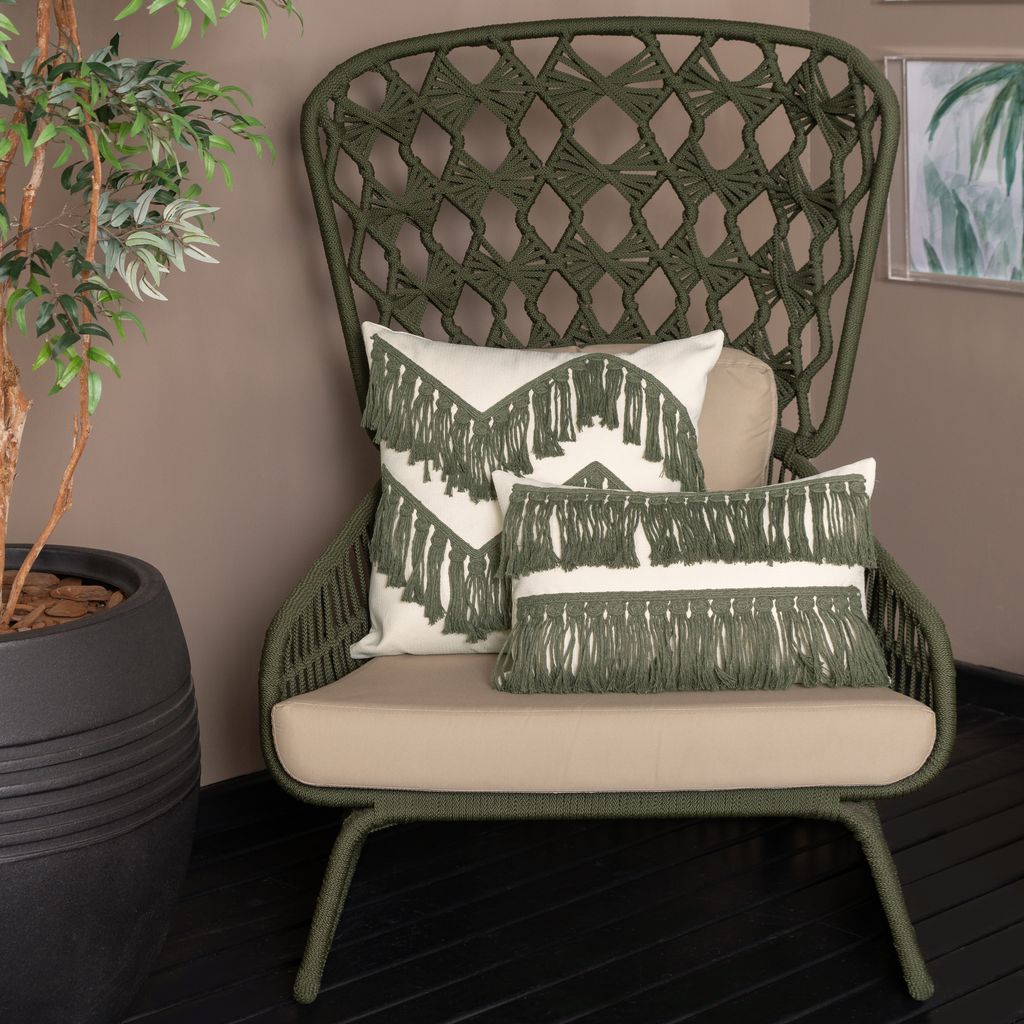 Foto ambientada de uma poltrona com duas almofadas da Decortextil macramê na decoração boho.