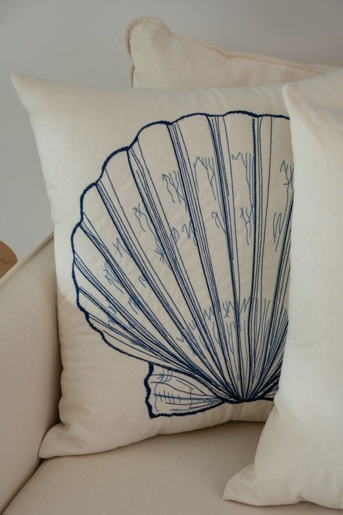 Detalhe de almofada bordada com preenchimento minucioso, mostrando a riqueza dos traços e a técnica aplicada no acabamento.