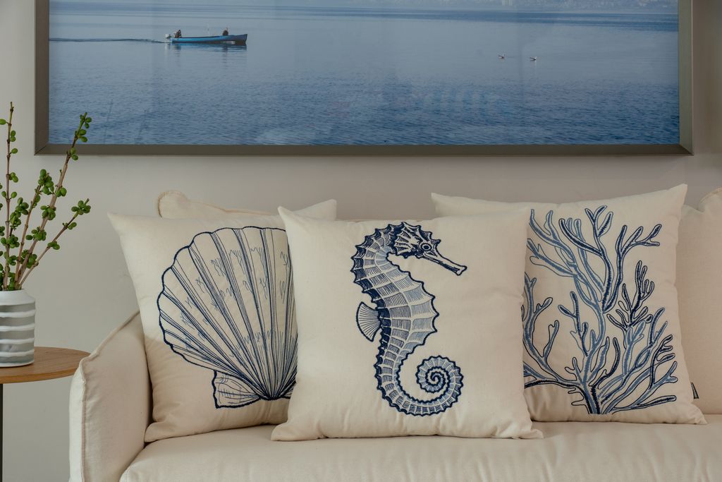 Almofadas bordadas decorativas em tom azul, com detalhes precisos e desenhos geométricos que destacam a textura e o acabamento sofisticado.