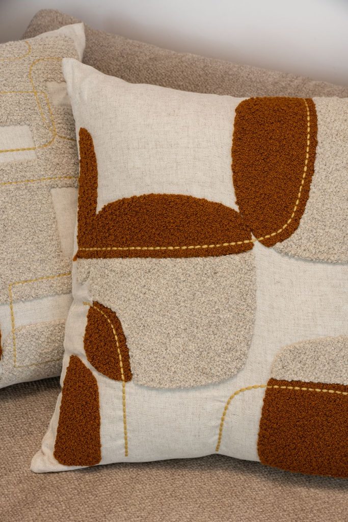 Detalhe do bordado bouclé em almofada de linho, evidenciando textura e design contemporâneo