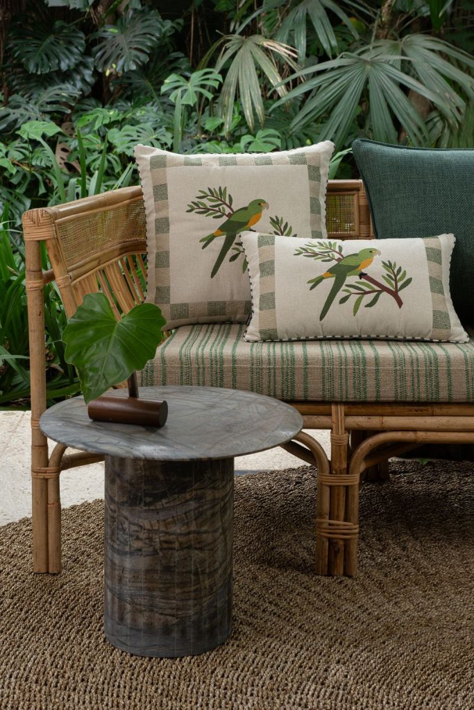 Detalhes de almofadas tropicais com bordados artesanais e elementos da natureza brasileira em composição contemporânea.
