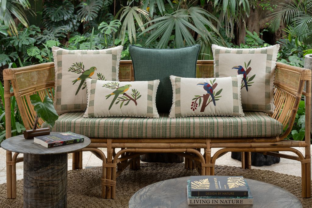 Composição de almofadas tropicais bordadas com desenhos inspirados em pássaros da fauna brasileira em ambiente sofisticado.