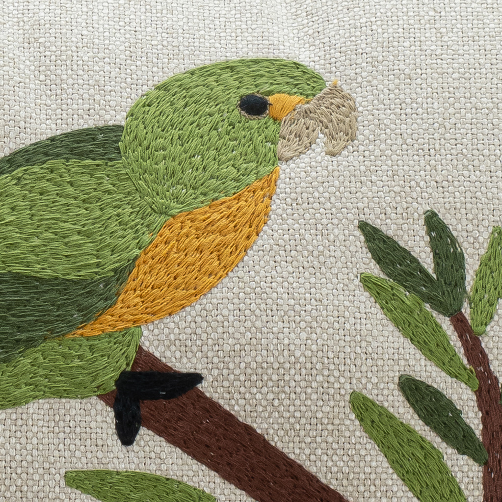 Detalhe do bordado artesanal em almofada decorativa tropical da Decortextil com textura sofisticada e riqueza nos acabamentos.